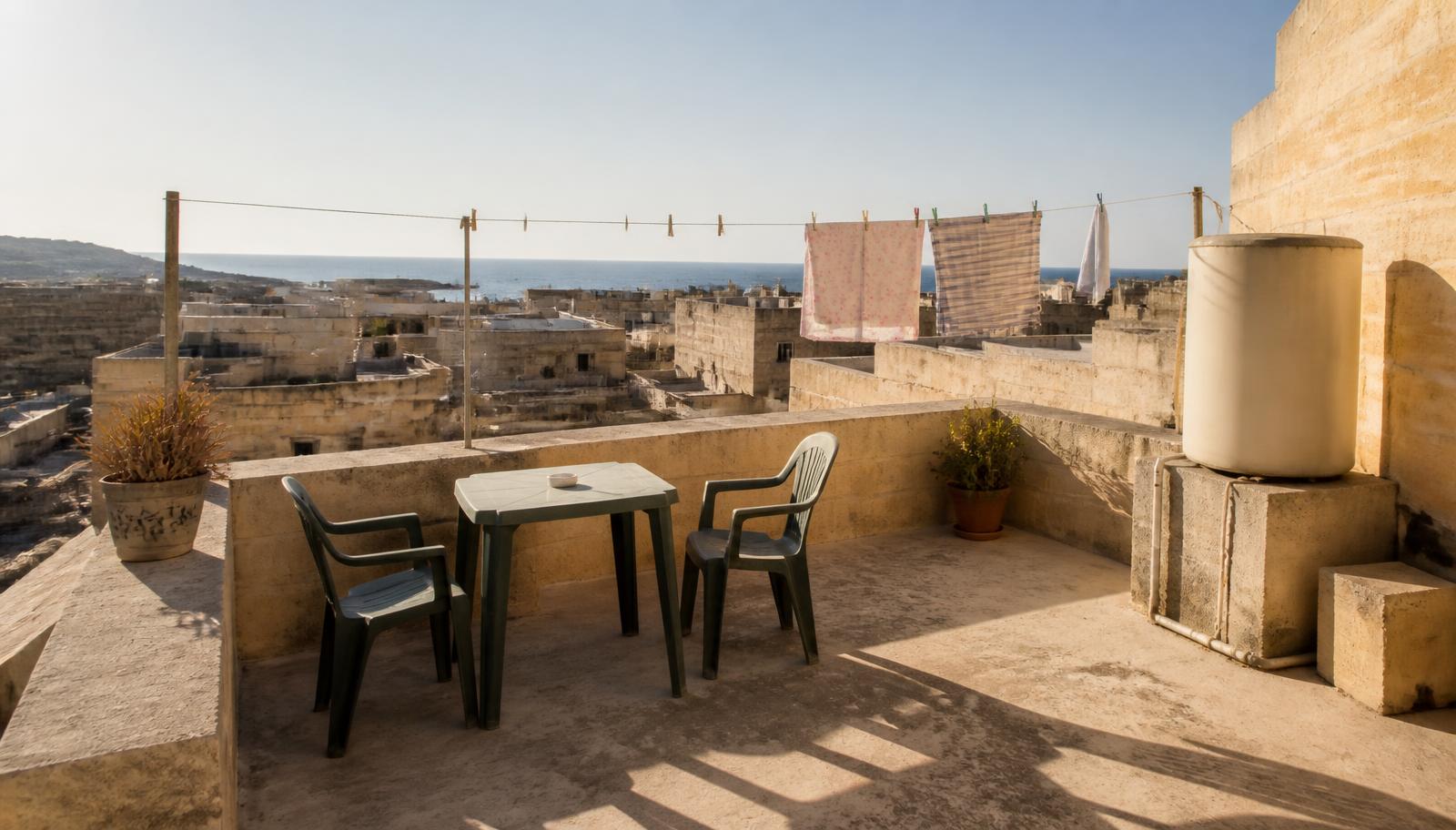 Dakterras van een Maltese woning met tafel, stoelen en uitzicht over de daken naar zee