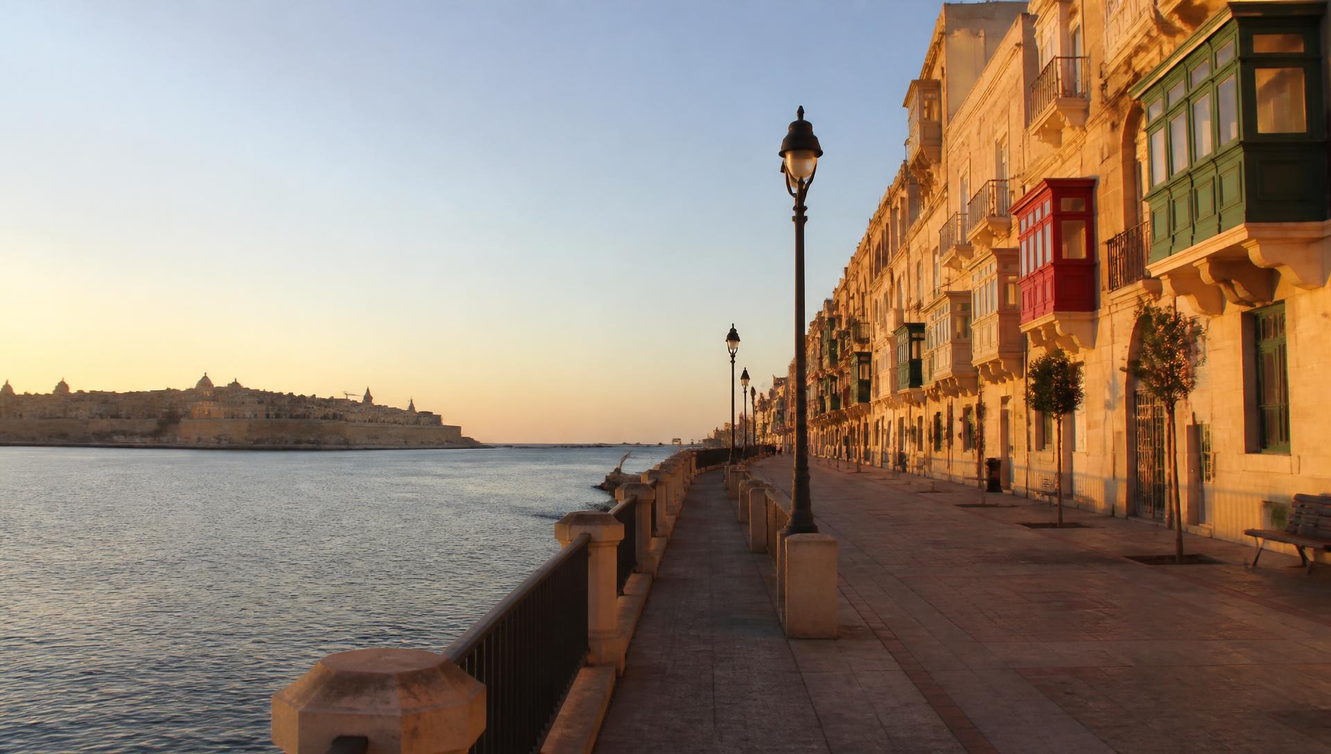 De promenade van Sliema bij zonsopgang met kalkstenen gevels en traditionele Maltese balkons
